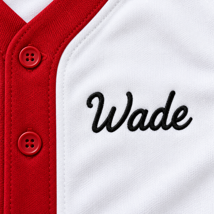 Close-up product mockup of black Wade script embroidery beside two red buttons on a white baseball jersey.
